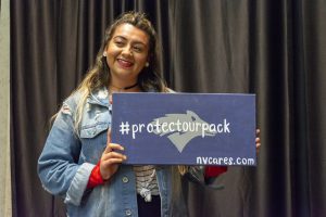college student holding a sign that says, # protect our pack